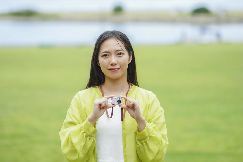 Woman holding a miniature camera during an outdoor walk