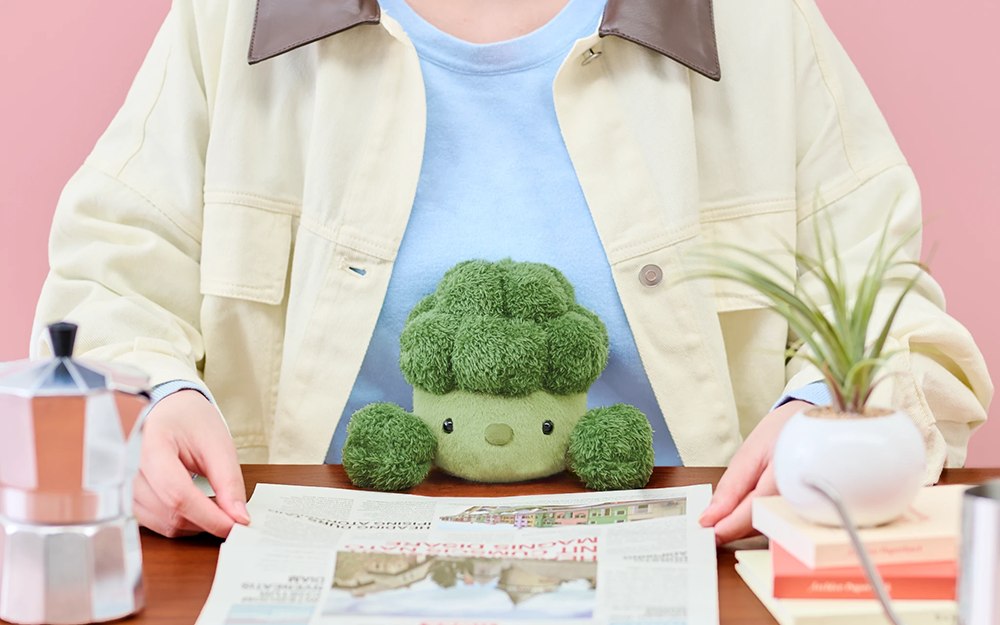 Broccoli posture plush at the desk edge during reading