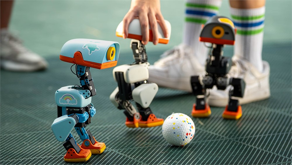 Microduck robots gathered around a ball on artificial turf