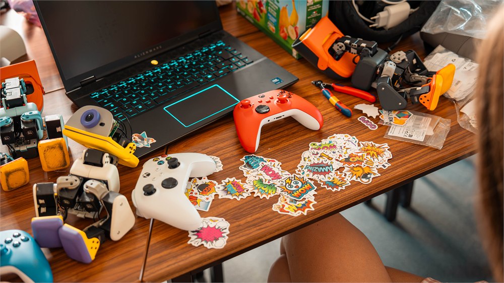 Overhead view of Microduck robots, a controller and accessories on a desk