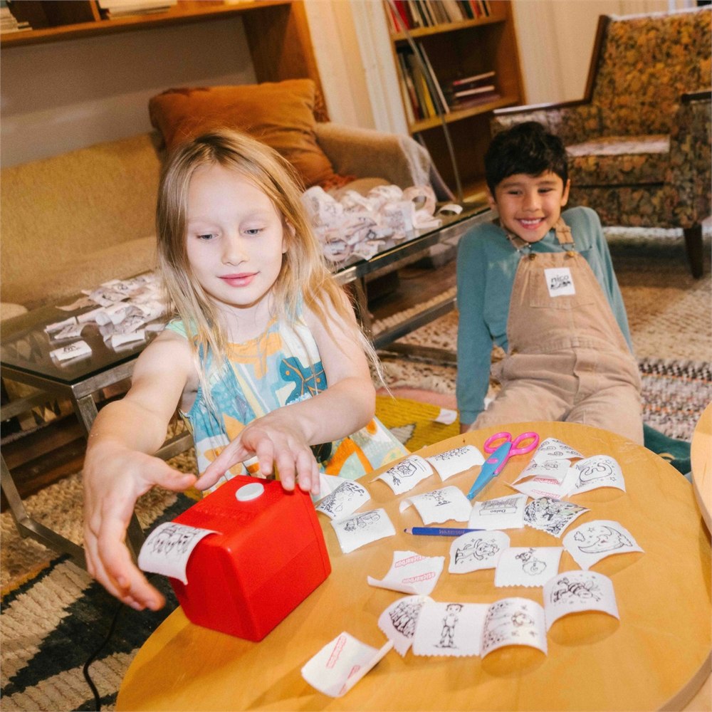 Two children making and coloring stickers at a table