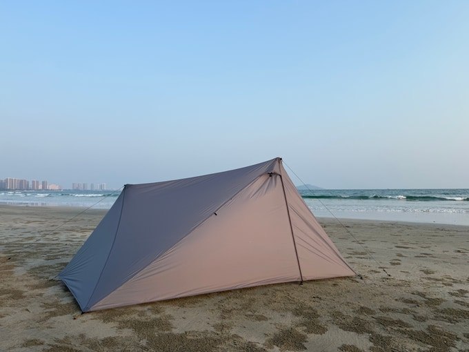 Light gray ROAMER solo tent pitched on a beach