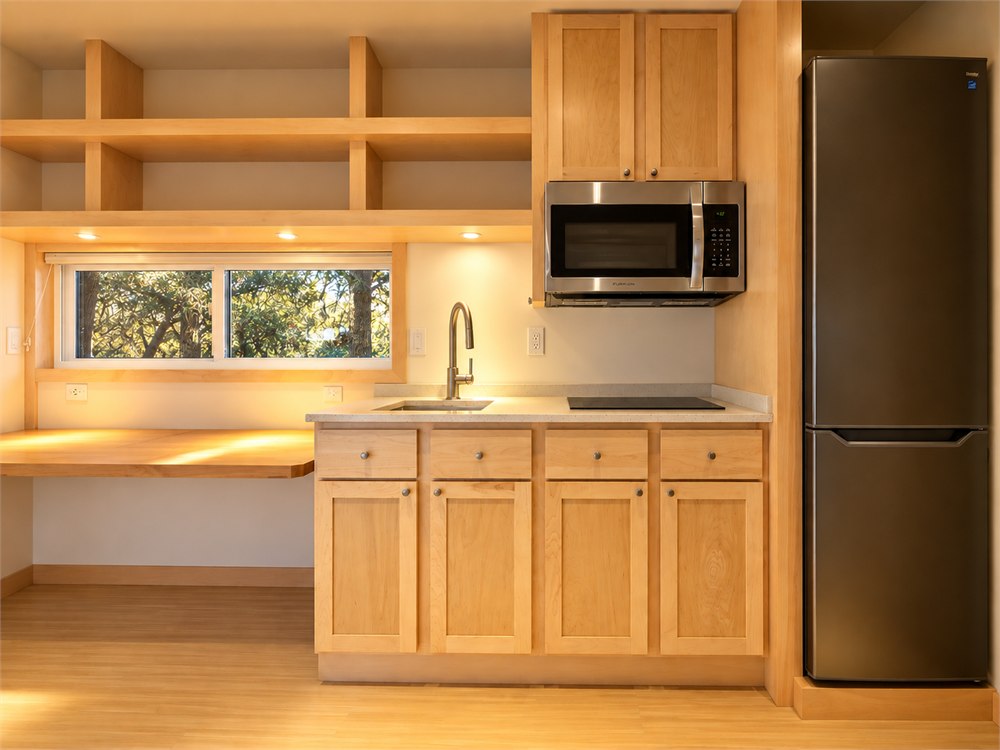 Compact kitchen with quartz counter and tall refrigerator