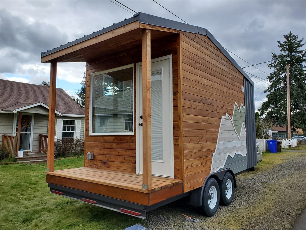 The Traveler tiny house exterior with cedar siding, porch and tandem wheels