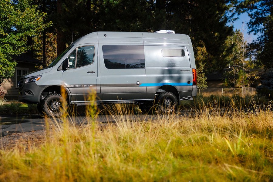 Silver GEAR MODE camper van parked beside trees